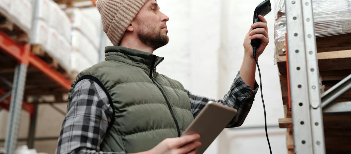 Amazon FBA prep center operator scanning a removed inventory carton with a handheld barcode scanner